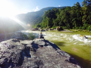 Heidi sitting on a big rock in front of the Rio Cangrejal, an epic river with class 5 rapids.